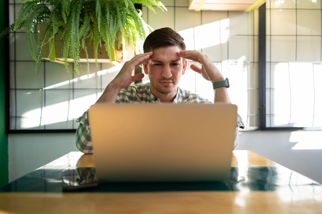 Hombre con gesto de frustración frente a un portátil en una oficina luminosa, representando problemas comunes en webs WordPress como lentitud, errores de maquetación o fallos técnicos.
